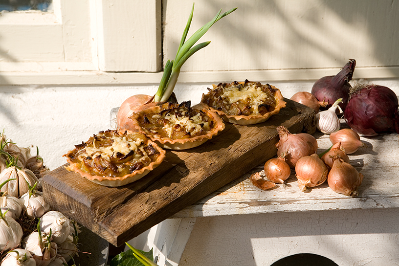 Drie uientaartjes op een houten plank met uien eromheen